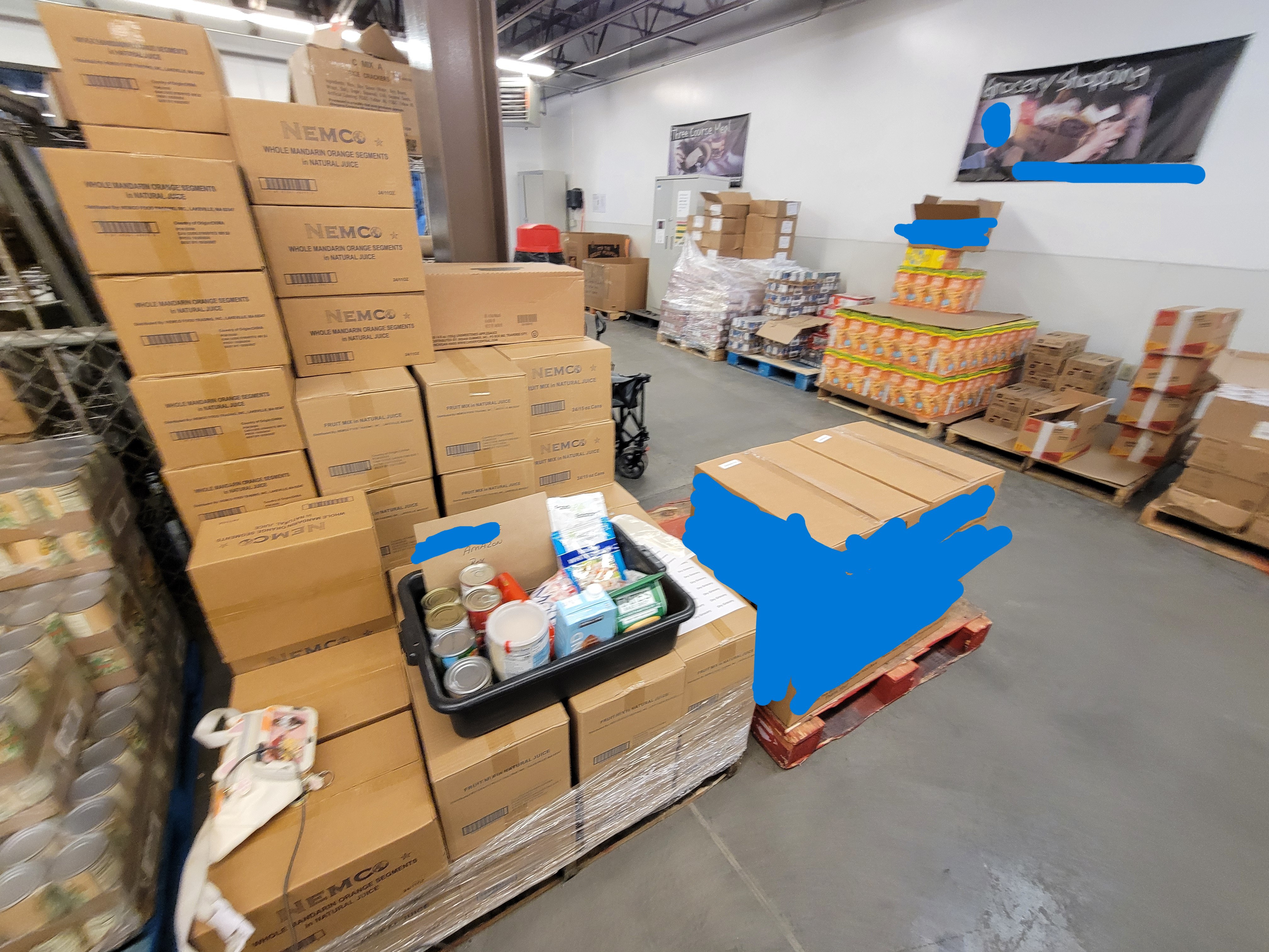 Pallets of food with a sample delivery box, cat fanny, and labels on top of one.